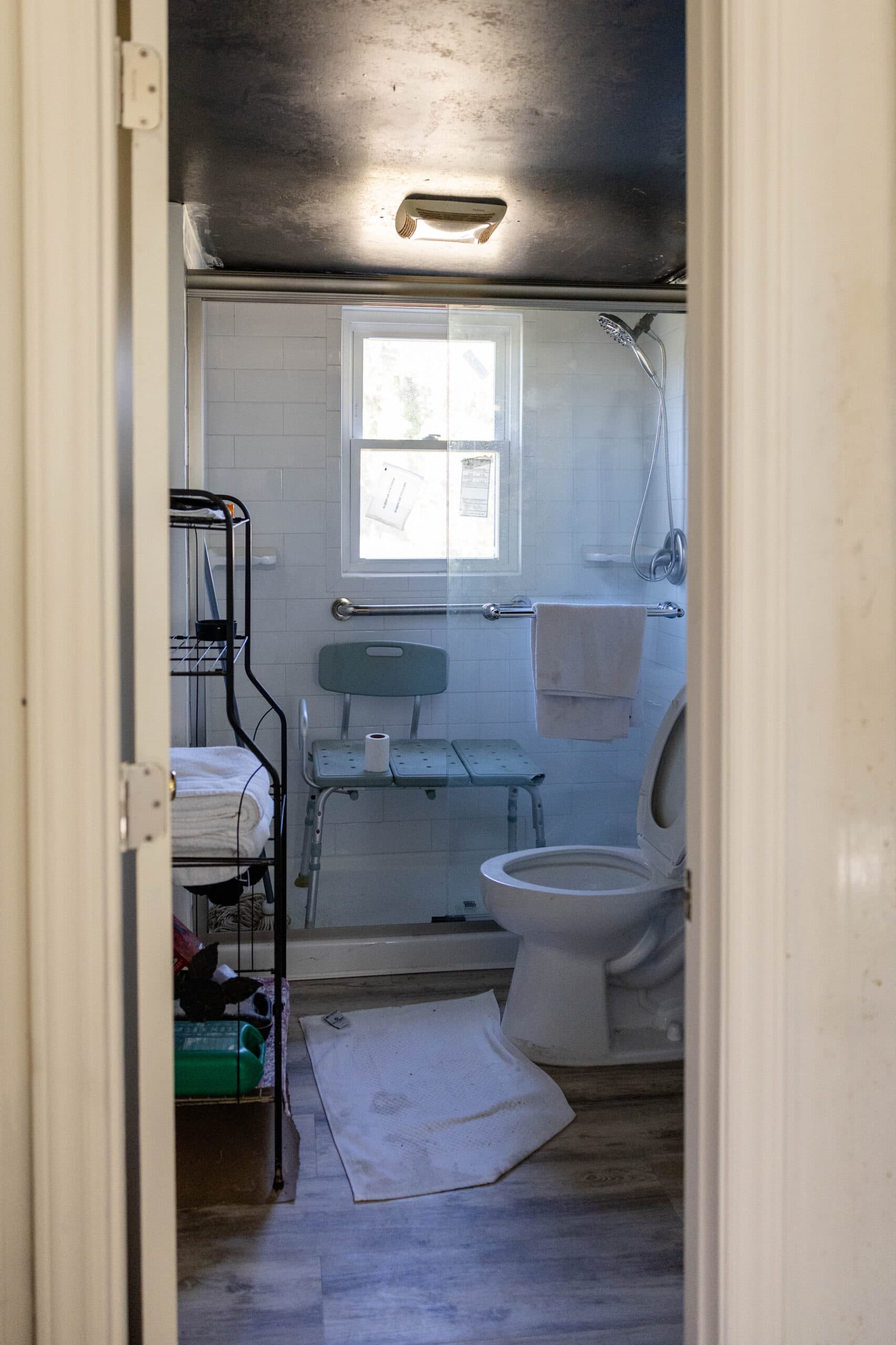 A bathroom with a shower chair and walk-in shower.