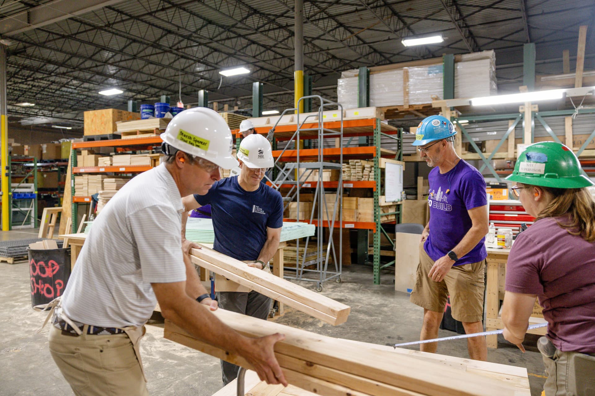 2026 CEO Build volunteers carrying planks of wood