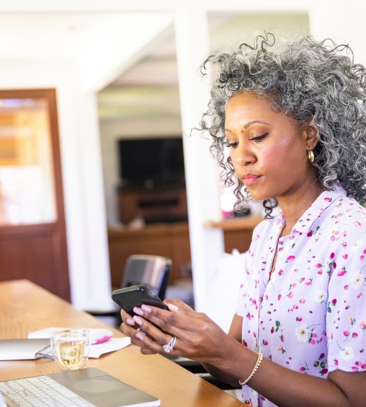 Woman looking at cell phone while on computer