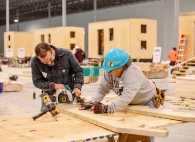 Habitat for Humanity volunteers sawing off some wood planks