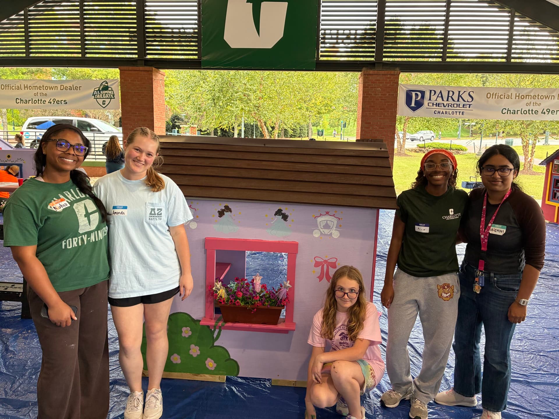 Volunteer group posing in front of princess themed playhouse