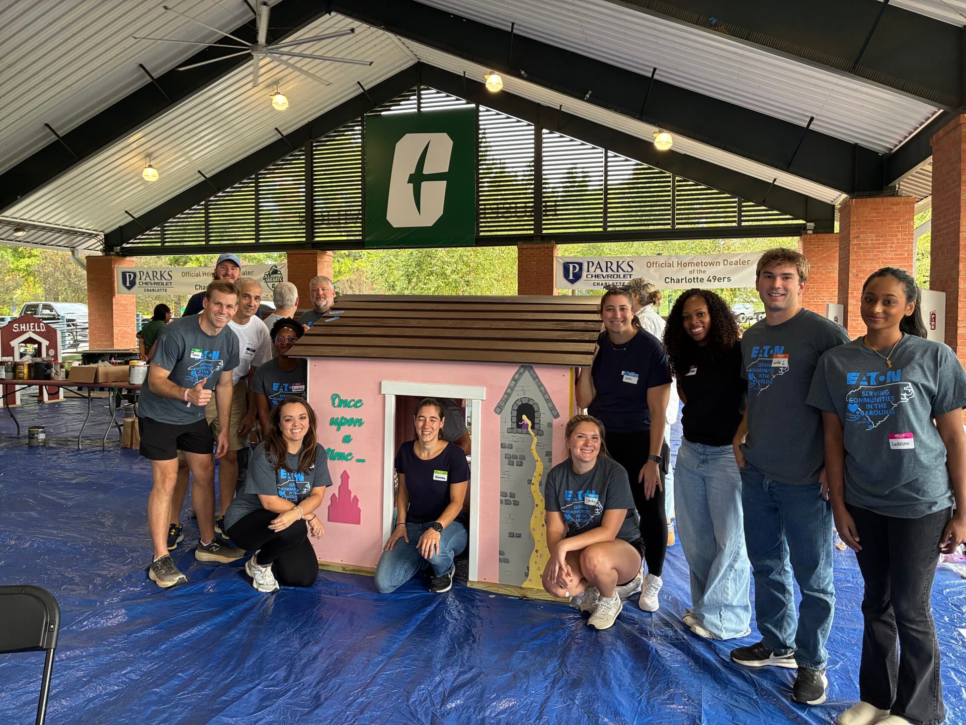 Volunteer group posing in front of princess themed playhouse