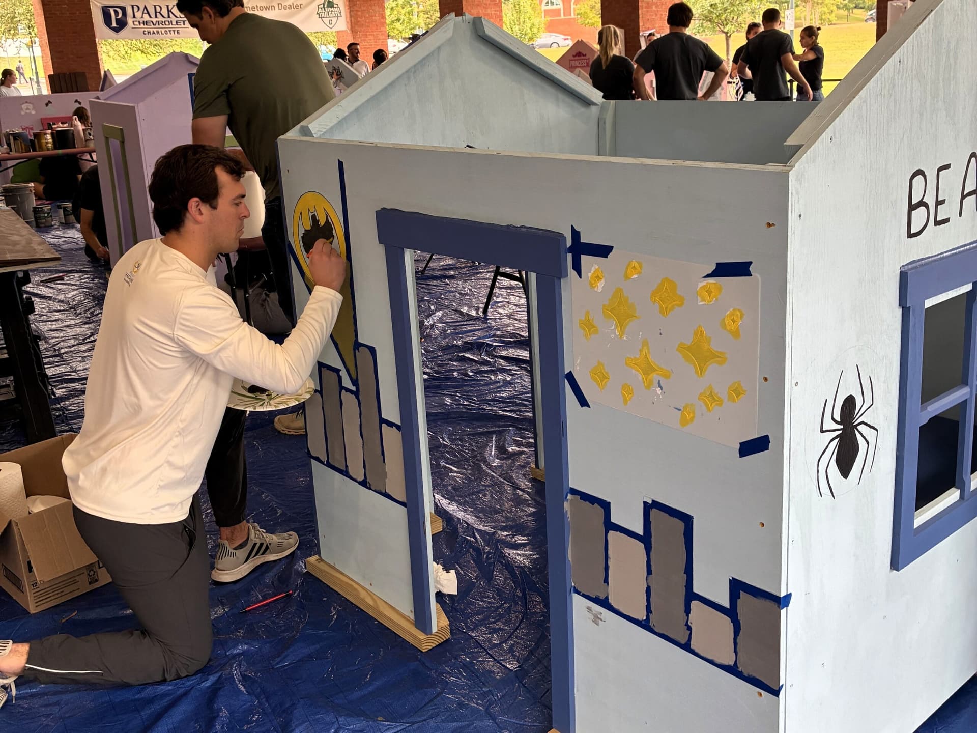 Volunteer painting Batman themed playhouse